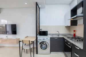 a kitchen with a washing machine and a table at Bel appartement piscine, 10 min stadium, souk, plage, bein sports in Agadir