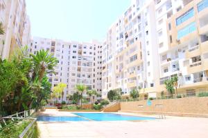 a swimming pool in front of a large building at Bel appartement piscine, 10 min stadium, souk, plage, bein sports in Agadir