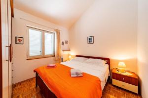 a bedroom with a bed with an orange blanket at Apartments by the sea Brna, Korcula - 20827 in Smokvica