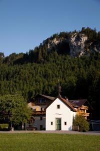 eine weiße Kirche mit einem Berg im Hintergrund in der Unterkunft Der Tannenhof in Reutte