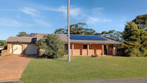 a brick house with solar panels on the roof at Collingwood Lodge by Experience Jervis Bay in Vincentia