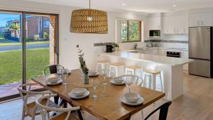 a kitchen and dining room with a wooden table and chairs at Collingwood Lodge by Experience Jervis Bay in Vincentia