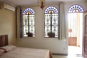 a bedroom with three stained glass windows and a bed at Casa da Josi - Pajuçara in Maceió