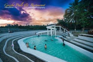 ein Pool in einem Resort mit Menschen im Wasser in der Unterkunft Gazebo Pools and Restaurant in Cabadbaran