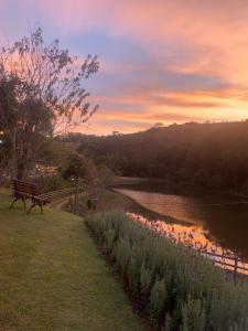 eine Parkbank neben einem Fluss bei Sonnenuntergang in der Unterkunft Pousada Shangri-lá in Cunha