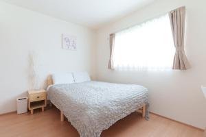 a white bedroom with a bed and a window at Habitacion Cottage Suzu in Fujikawaguchiko