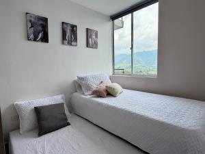 a white bedroom with a bed and a window at Acogedor Refugio Céntrico con Parking Privado in Armenia