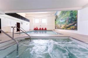 a swimming pool in a building with a painting on the wall at Prestige Radium Hot Springs Resort, WorldHotels Crafted in Radium Hot Springs