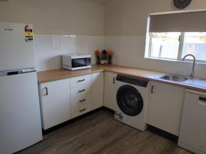 a kitchen with a washing machine and a microwave at The Flat on Muddy in Moonta