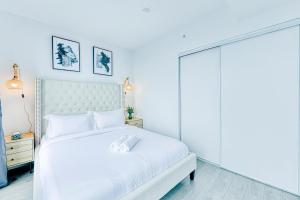 a white bedroom with a white bed and a glass door at RivetStays - The Jarvis in Toronto