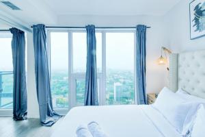 a bedroom with a large bed with blue curtains at RivetStays - The Jarvis in Toronto