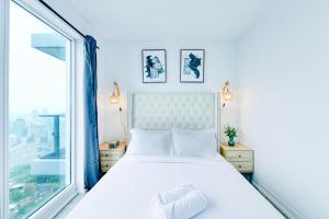 a white bed in a room with a large window at RivetStays - The Jarvis in Toronto