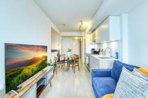 a living room with a blue couch and a kitchen at RivetStays - The Jarvis in Toronto