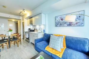 a living room with a blue couch and a kitchen at RivetStays - The Jarvis in Toronto