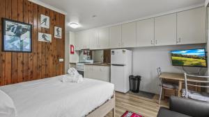 a bedroom with a white bed and a kitchen at Alpine Haven 4 in Mount Hotham