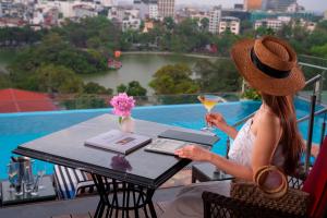 a woman sitting at a table with a drink at The Oriental Jade Hotel in Hanoi