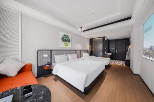 una camera da letto con un grande letto bianco e un divano arancione di Chenfeng Hotel Jingdezhen Taoyangli People's Square Branch a Jingdezhen