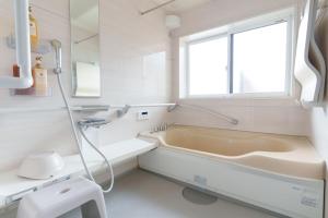 a bathroom with a bath tub and a window at GuestHouse道 in Fujiyoshida