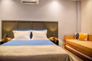 a bedroom with a large bed with blue and white pillows at Studio Brisa da Ferradura - Búzios in Búzios