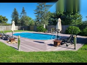 a pool with chairs and umbrellas on a wooden deck at Barn in Aubigné-Racan with Heated Pool in Aubigné-Racan