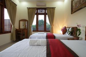 sypialnia z dwoma łóżkami i oknem w obiekcie Taman Ayu Ubud w mieście Ubud