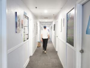 Un uomo che cammina lungo un corridoio in un corridoio dell'ospedale di Attic Backpackers ad Auckland