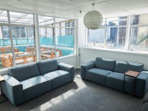 a living room with two blue couches in front of windows at Attic Backpackers in Auckland +50 photos