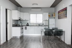 a kitchen with white cabinets and a glass table at Salt Lake view Apartment in Larnaca