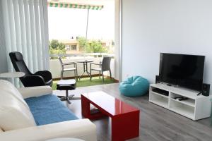 a living room with a white couch and a tv at Salt Lake view Apartment in Larnaca