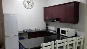 cocina con encimera, microondas y reloj en Topanga Holiday Home en Uvongo Beach
