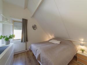 a attic bedroom with a bed and a window at Sunny Garden Stay near Sea in Wemeldinge