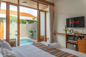 a bedroom with a bed and a tv and a pool at Comoda Seminyak in Seminyak +23 photos