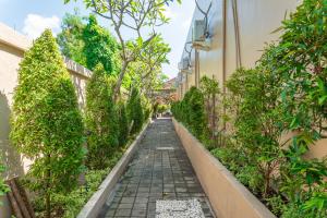 a walkway between two buildings with trees at Comoda Seminyak in Seminyak