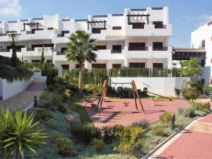 un grande edificio bianco con parco giochi di fronte di Apartamento encantador con piscina comunitaria en San Juan de los Terreros - ES-376-17 a Pulpí