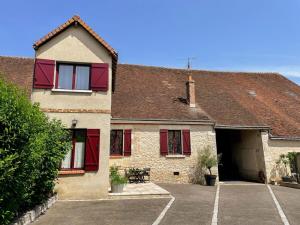 una casa di mattoni con persiane rosse e un parcheggio di Gîte charmant à Veuzain-sur-Loire, proche des châteaux - FR-1-491-470 a Veuzain-sur-Loire