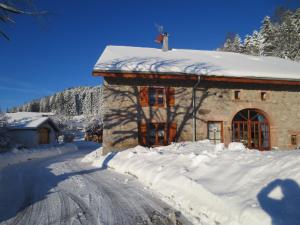 a building covered in snow next to a road at Gîte du Champ du Bois : Confort au cœur des Vosges - FR-1-589-820 in Le Tholy