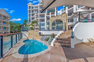 a balcony with a swimming pool and a building at The Drift - Airlie Two in Airlie Beach