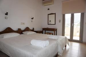 una camera da letto con un letto con lenzuola bianche e una finestra di Valentino Apartments a Balíon