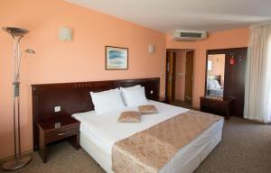 une chambre avec un grand lit avec des draps et des oreillers blancs dans l'établissement Hotel Divesta - self check in, à Varna