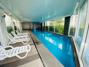 a swimming pool with white lounge chairs next to a building at Departamento Alto Libertad Meseta Coraceros in Viña del Mar