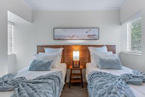 Un dormitorio con dos camas y una lámpara sobre una mesa. en The Drift - Airlie Two, en Airlie Beach 31 fotos más