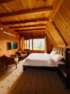 Luxury Timber Resorts and Hotels Cottages in Upper Neelum, Keran, AJK في Chak: غرفة نوم بسرير كبير ونافذة كبيرة