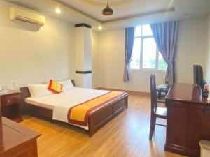 a bedroom with a bed and a desk and a television at DONA Hotel in Can Tho