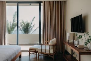 a hotel room with a bed and a chair and a window at A Stay In CiCi in Ấp An Lộc A