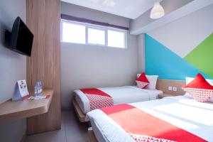 a hotel room with two beds and a tv at Flagship 101 Apple Platinum in Jakarta