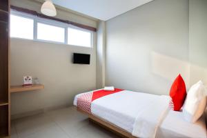 a bedroom with a bed with red pillows and a window at Flagship 101 Apple Platinum in Jakarta +18 photos
