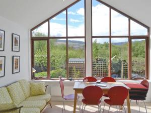a living room with a table and chairs and a large window at 3 Barf Cottages in Portinscale