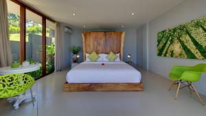 a bedroom with a white bed and a green chair at Malimbu Cliff Villa by Elite Havens in Senggigi +13 photos