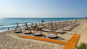 eine Gruppe von Stühlen und Sonnenschirmen an einem Strand in der Unterkunft La Boheme - Adults Only in Obsor