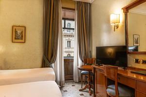 a hotel room with a bed and a desk and a television at Hotel Miami in Rome